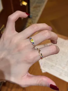 Detail showing two vintage style colorful zircon leaf open rings on a hand model.