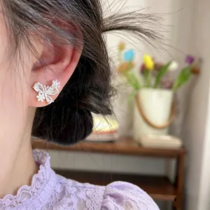 Detailaufnahme von süßen Schmetterlings- und Blumenohrsteckern, am Ohr getragen