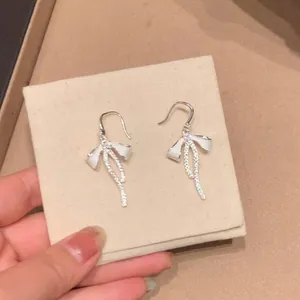 Detailed macro view of silver bow earrings with elegant sparkling zircon tassels