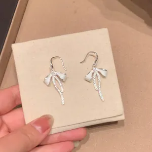 Detailed view of elegant silver bow earrings with sparkling dangling zircon tassels