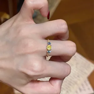 Close-up of a vintage-style ring with five colorful zircons on an index finger.
