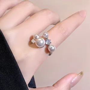 Close-up of elegant open ring featuring white pearls and a sparkling zircon stone