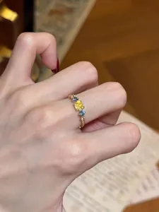 Exquisite vintage style gold open ring with vibrant yellow and blue zircon details on finger