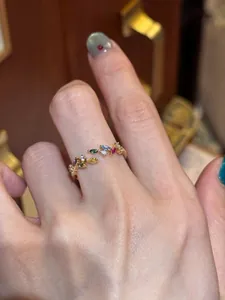 Detailed view of a vintage-style gold ring with colorful zircon leaves on a finger.