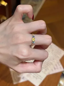 Close-up of a vintage leaf-style ring with vibrant yellow and blue zircons on finger