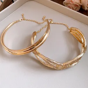 Close-up detail of golden pleated cross-wrapped necklaces in a vintage luxury style