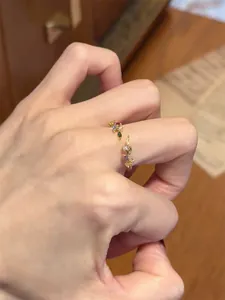 Close-up of elegant gold leaf open ring featuring vibrant multi-colored zircons