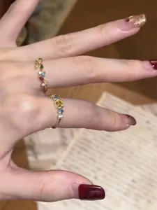 Close-up of elegant vintage-style gold rings with colorful zircons on a manicured hand