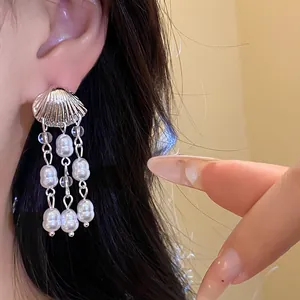 Close-up of vintage shell earrings with white pearl tassels and silver-tone finish