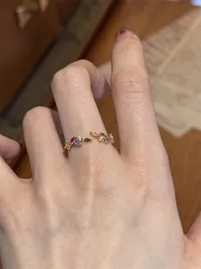 Detailed close-up of a vintage style open ring with colorful zircon leaves on finger