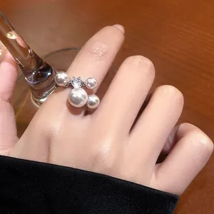 Close-up detail of vintage-style zircon and pearl open ring on finger