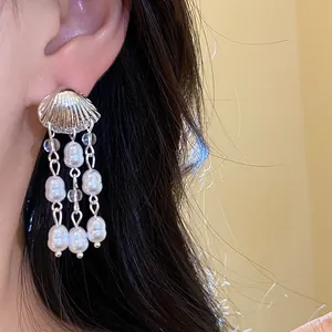 Detailed close-up of vintage silver shell earrings with elegant pearl tassels worn on ear