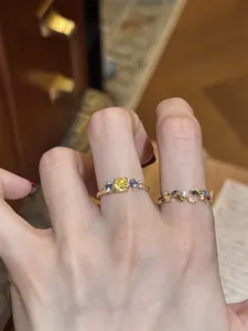 Macro view of a gold leaf ring set with vibrant multi-colored zircons on fingers.