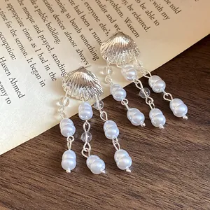 Detailed view of elegant shell-shaped silver earrings with dangling pearl tassels