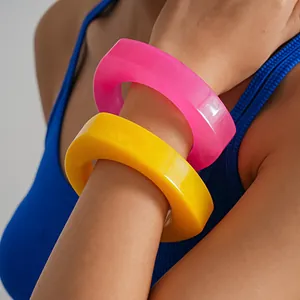 Nahaufnahme von klobigen unregelmäßigen geometrischen Harzarmreifen in Pink und Gelb