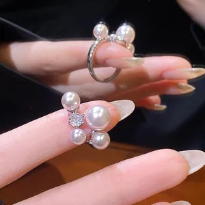 Close-up of elegant open ring featuring four lustrous pearls and a sparkling zircon