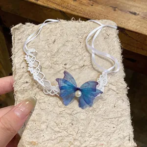 Detail view of the delicate blue chiffon butterfly and pearl on a white lace choker.