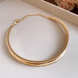 Detailed view of the elegant golden twisted metal choker necklace on a white surface