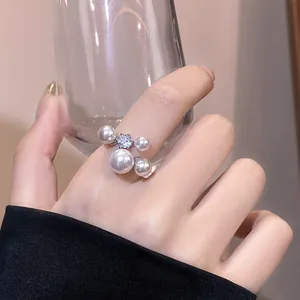 Macro view of elegant open ring showcasing pearls and zircon sparkle on the finger.