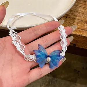 Detail shot of blue chiffon butterfly and pearl on a white lace choker necklace