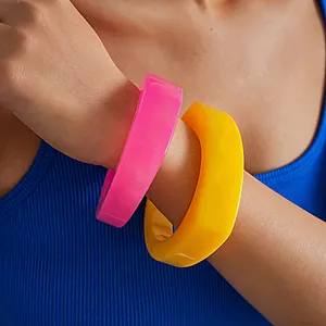 Nahaufnahme von neonpinken und gelben Harzarmreifen mit unregelmäßigem Design