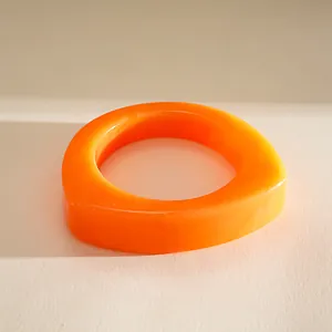 Detailaufnahme eines leuchtend orange marmorierten Harzarmbands in unregelmäßiger Form.