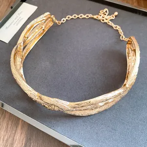 Detailed view of a gold-toned crumpled metal wrapped necklace with intricate texture.