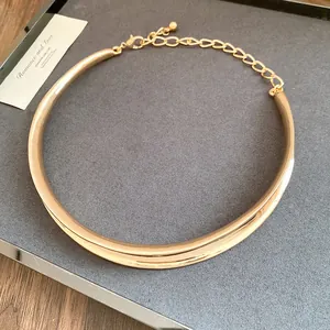 Detail view of a vintage gold pleated cross choker necklace on a grey display
