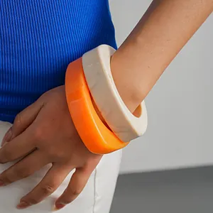 Detailansicht von klobigen, unregelmäßigen Harzarmbändern in kräftigem Orange und Marmor