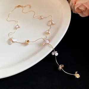 Elegant gold-tone Y-necklace featuring white enamel flower charms and tassel drop