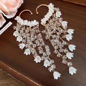 Detail von französischen Vintage-Blumen-Ohrklemmen mit weißen Blüten und Perlen.