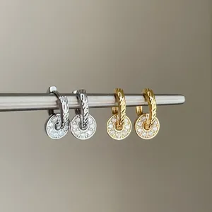 Detail view of elegant gold and silver hoop earrings with pavé zircon round pendants