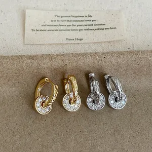 Detailed view of gold and silver hoop earrings with shimmering zircon round pendants