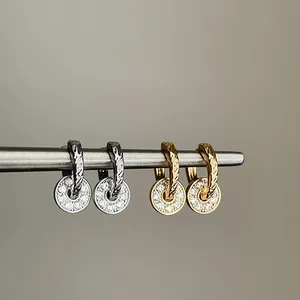 Detail of elegant silver and gold hoop earrings with sparkling zircon pendant