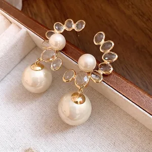 Orecchini pendenti vintage dorati con perle eleganti e dettagli in cristallo sfaccettato.