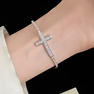 Dettaglio di un bracciale color argento con croce incastonata di zirconi sul polso