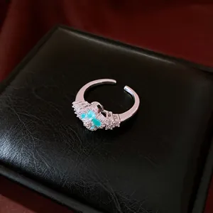 Elegant silver-toned flower ring with blue zircon stones on a black display base.