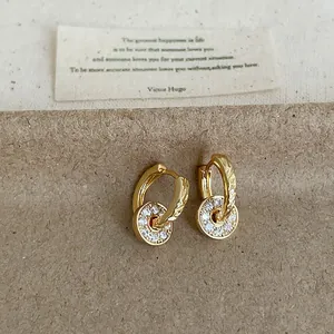 Close-up of gold hoop earrings with pave zircon round pendants and textured hoops