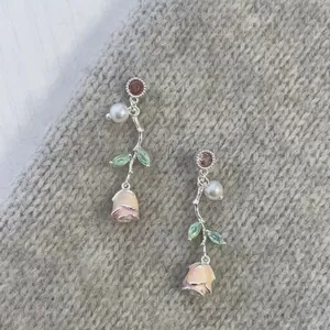 Close-up of sweet rose flower earrings with pearls on a grey knitted background