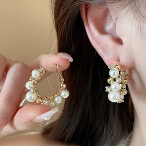 Détail de magnifiques créoles plaquées or 14k avec perles blanches et zircons étincelants
