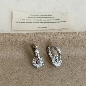 Detailed macro view of silver hoop earrings featuring sparkling round zircon drop pendants.