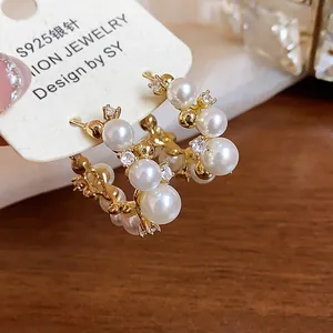 Gros plan de boucles d'oreilles créoles dorées 14 carats avec perles et zircon.