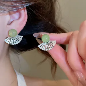 Primo piano di orecchini a ventaglio in stile cinese con perla verde e bambù