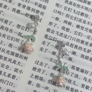 Close-up of elegant rose and pearl drop earrings on a literary background