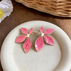 Elegant pink enamel flower stud earrings with gold plating displayed on white plate