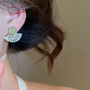 Primo piano di orecchino a ventaglio cinese con perla verde e motivo in bambù