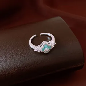 Macro detail of elegant silver ring featuring a green clover flower motif with pavé crystals