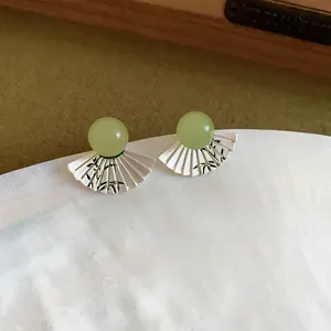 Dettaglio di orecchini a ventaglio in stile cinese con motivo a bambù e pietra verde