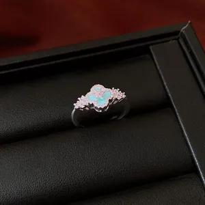 Close-up of retro silver ring with pink zircons and green flower center in black box