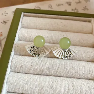 Vista dettagliata di orecchini a ventaglio con perle di giada verde e motivi di bambù.